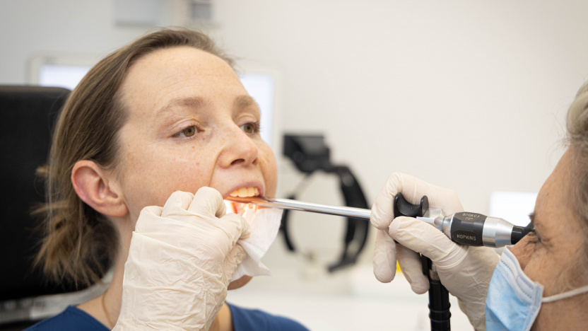 Een vrouw tijdens een laryngoscopie met een niet flexibele endoscoop in de mond